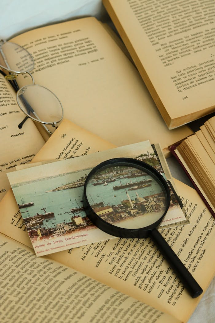 A vintage magnifying glass on open books with a postcard. Perfect for nostalgic and educational themes.