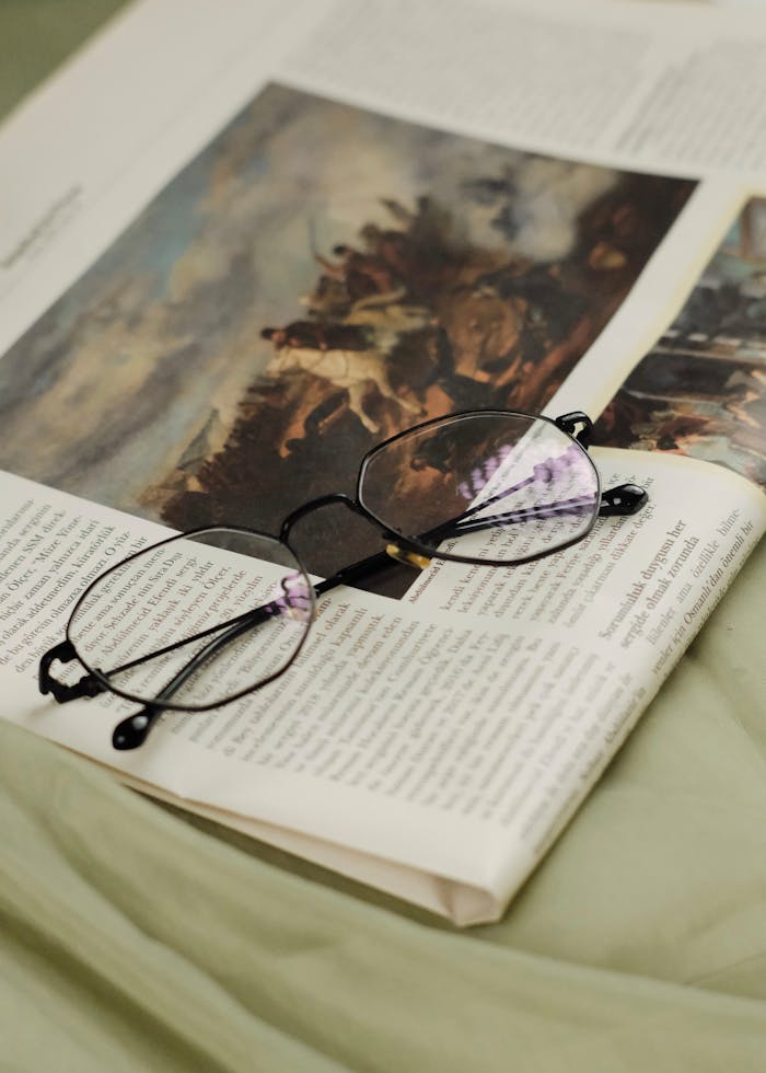 Close-up of eyeglasses on an open magazine, showcasing elegant simplicity with selective focus.